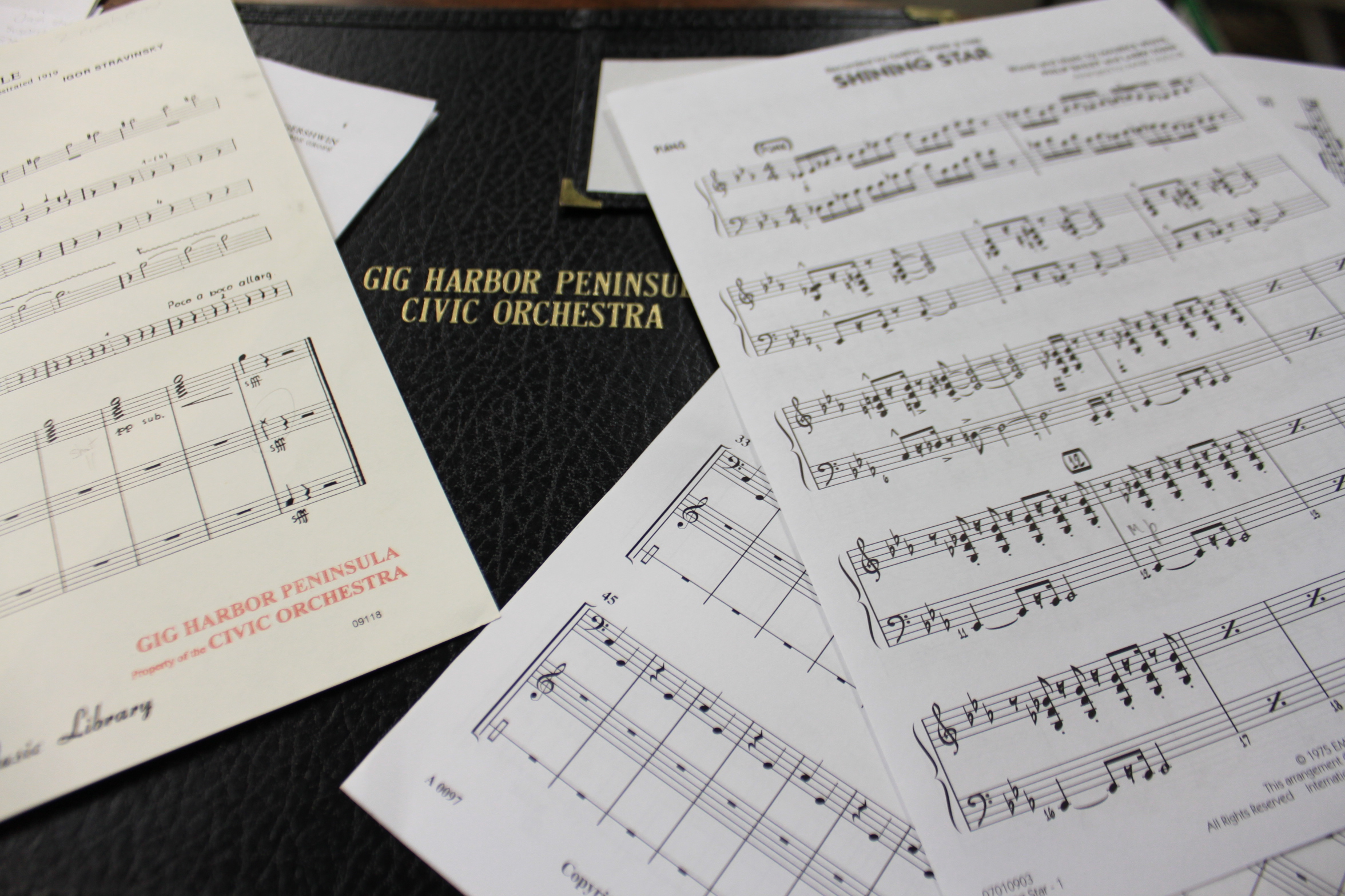 Sheet music on a folder with Gig Harbor Peninsula Civic Orchestra in gold