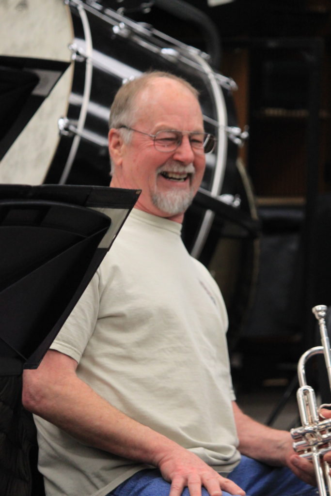 A man smiling while holding a trumpet