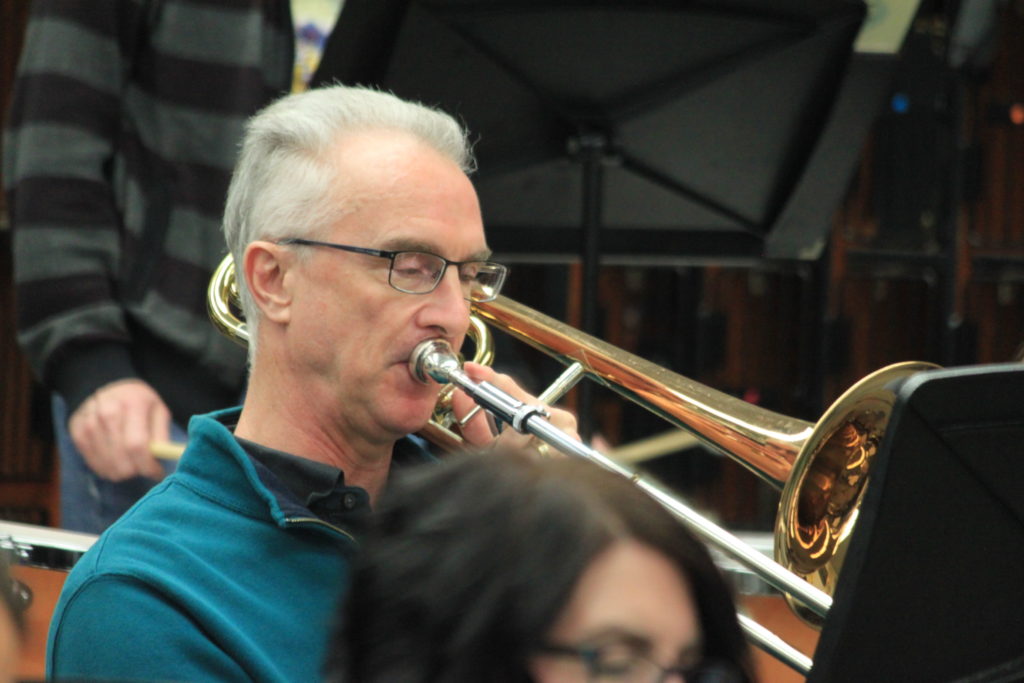 An older man playing a trombone