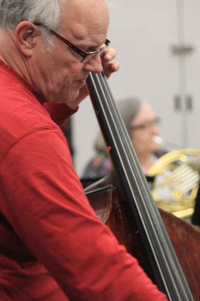 A close up of older man playing the string base